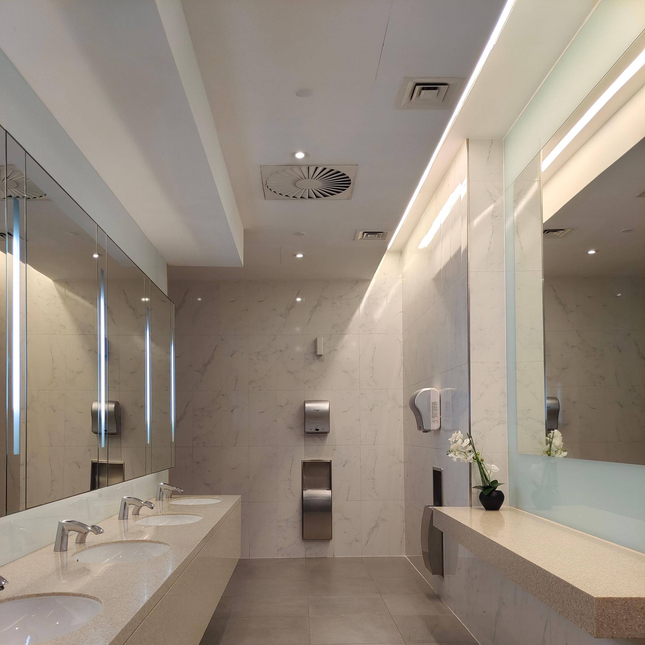 Commercial restroom with a triple vanity and marble tile walls