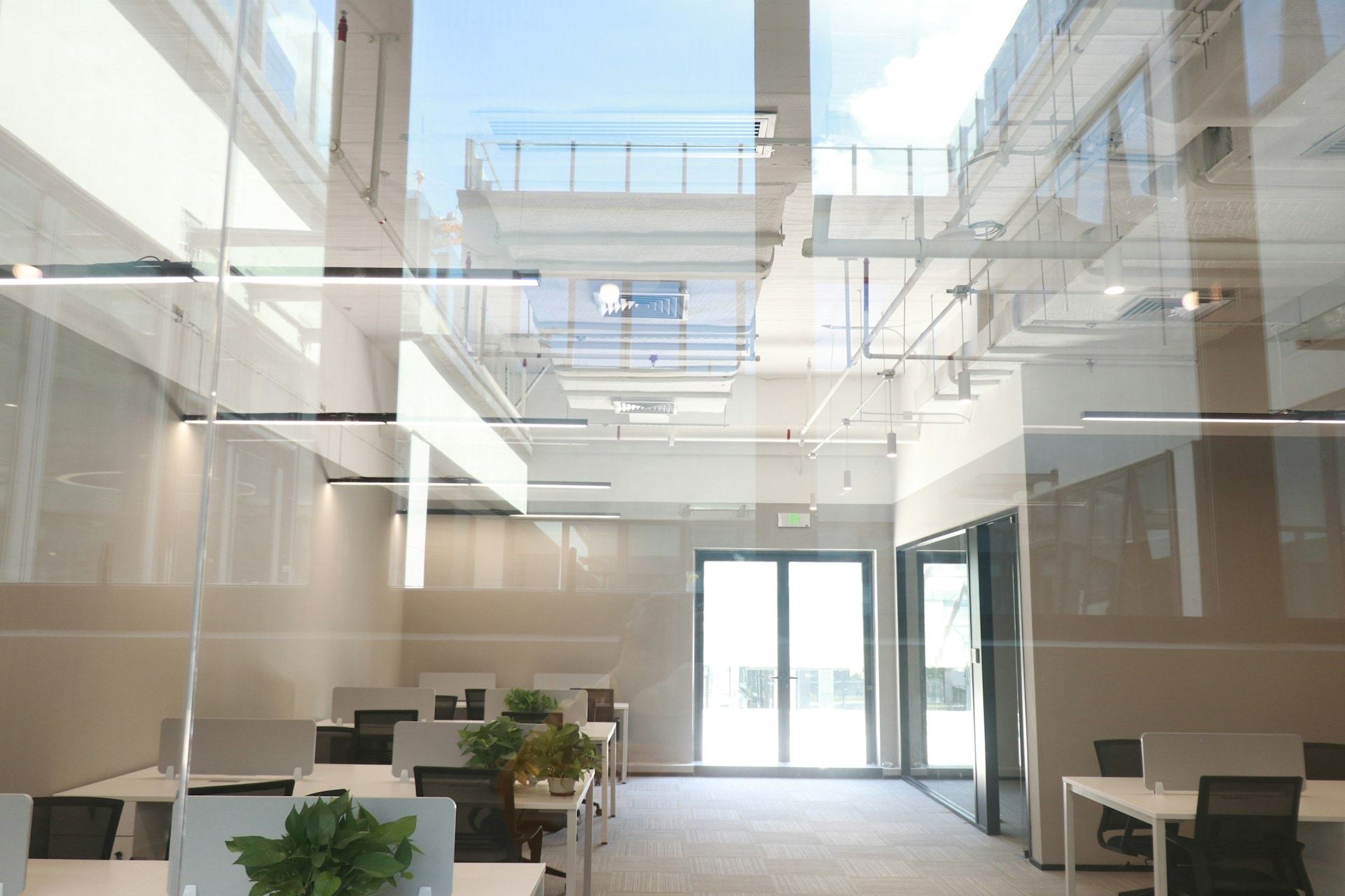 Open-plan office with white desks beneath a skylit atrium
