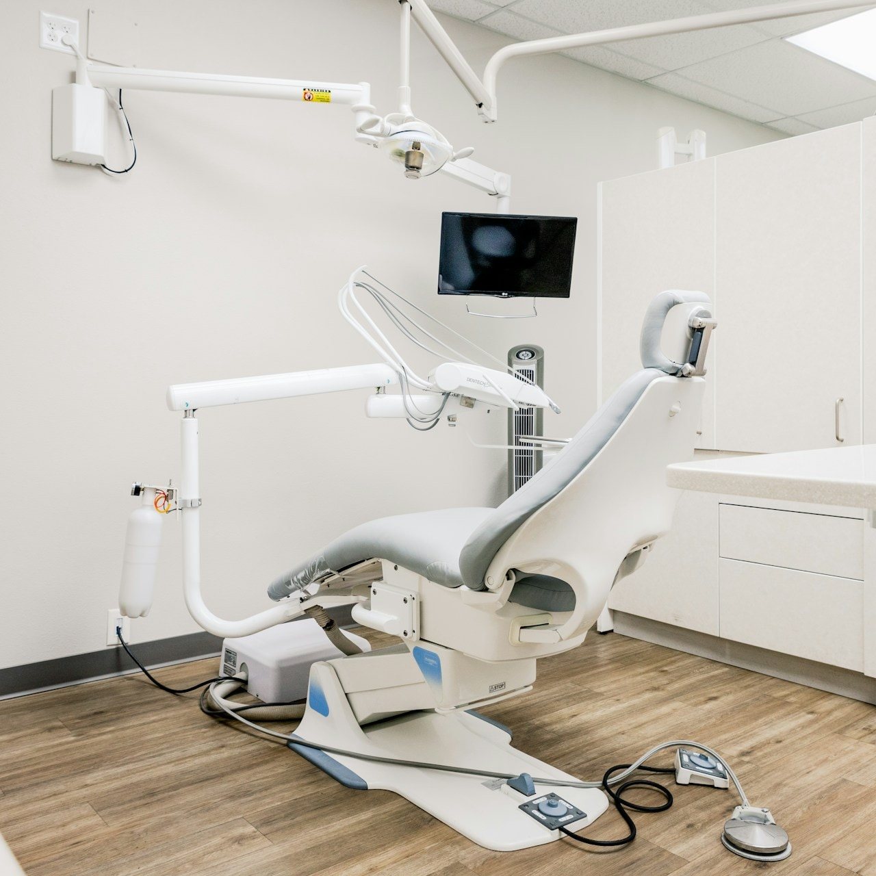 Bright dental operatory with a patient chair, overhead light and instrument tray