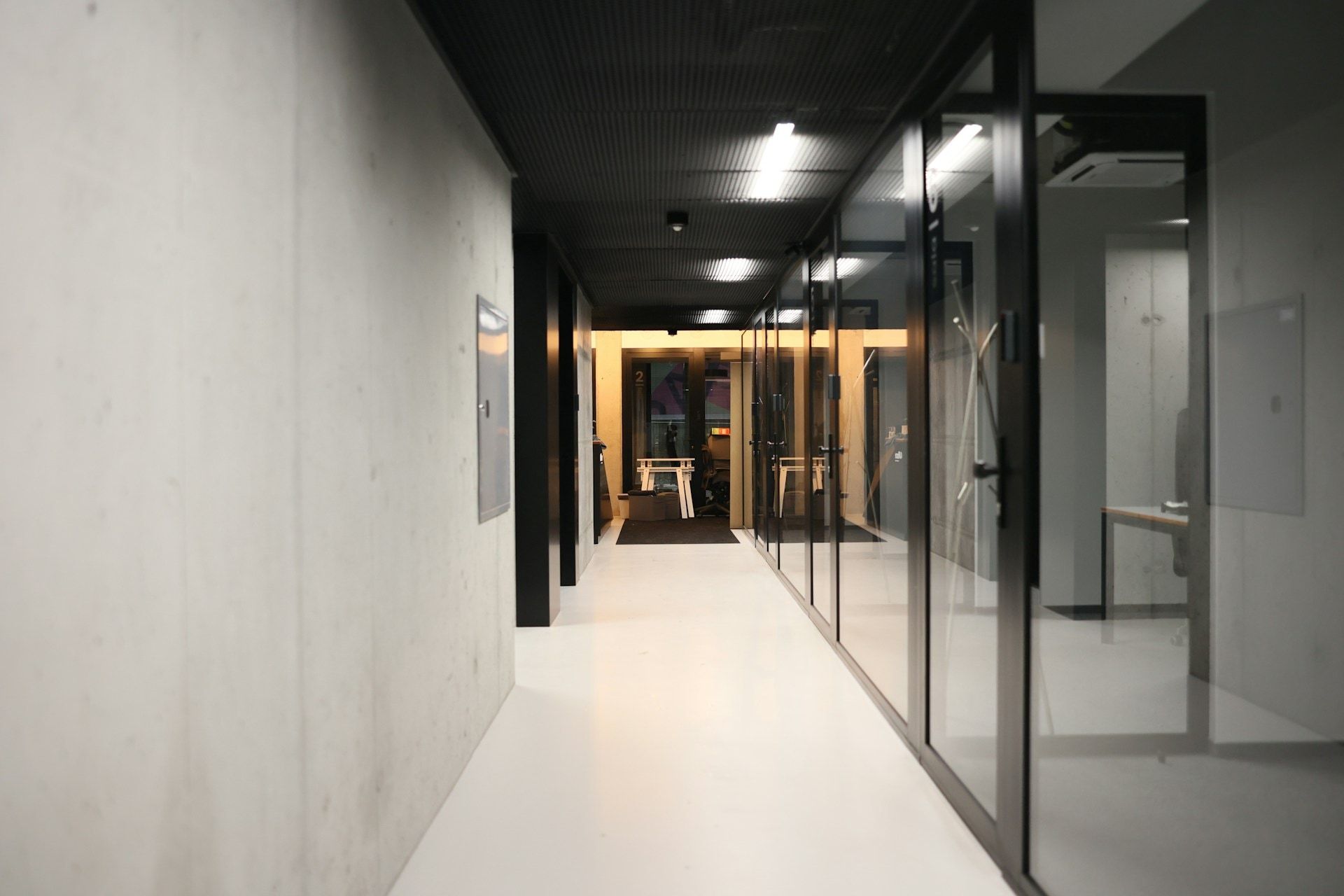 Office corridor lined with glass-walled meeting pods