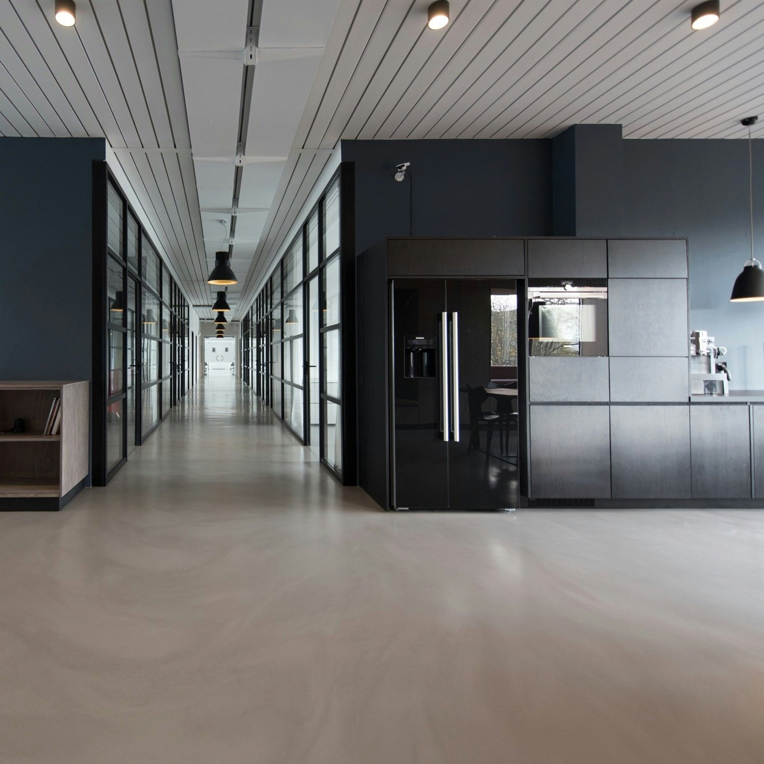 Open office space with dark accent walls and a break-area kitchenette