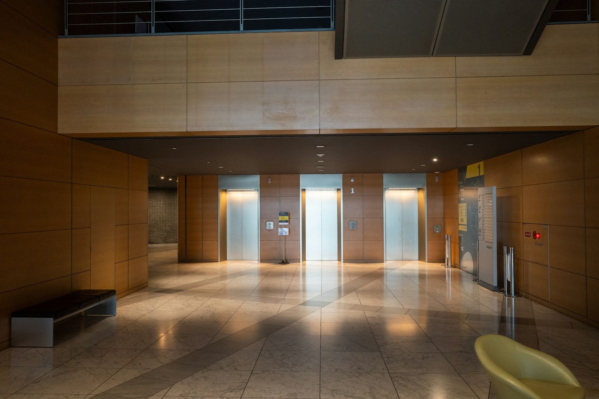 Elevator lobby with wood paneling and polished stone floors